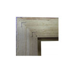 Underside of a picture frame corner showing two inserted V-nail wedges for a professional joint